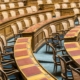 Rows of wooden chairs with cane backs and leather desks in a legislative chamber